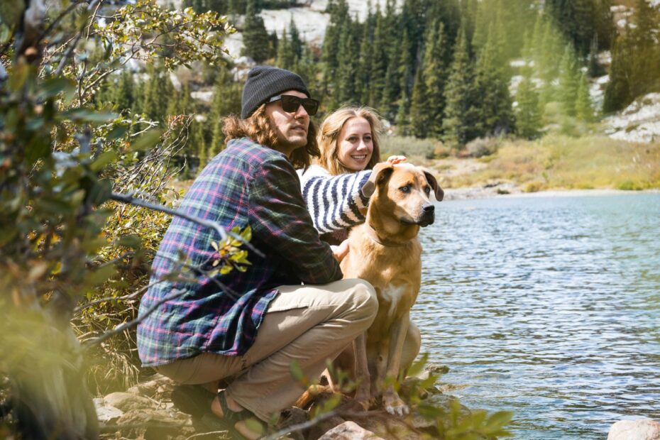 woman in purple and white striped long sleeve shirt sitting beside brown short coated dog